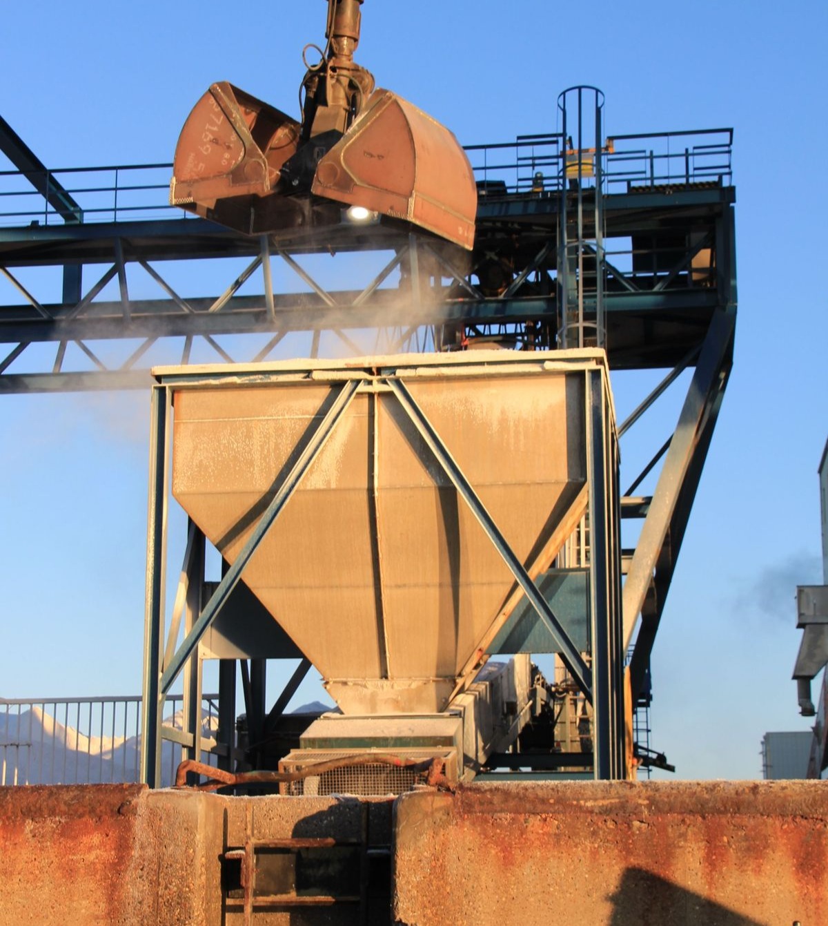 Material handling hopper and clamshell grab transferring bulk material